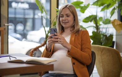 Nosečnica z mobitelom v roki.